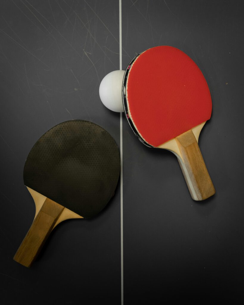 Photo d'une table de ping pong avec deux raquettes posées dessus et une balle